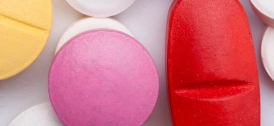 Gélules et comprimés pharmaceutiques disposés sur une surface claire